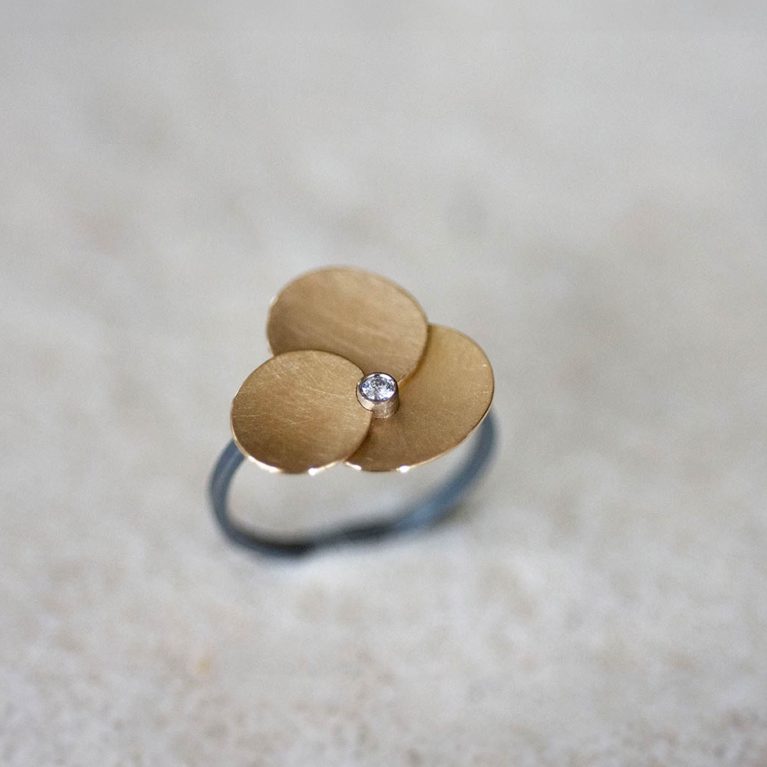 Anillo de oro con tres discos satinados y diamante central en diseño contemporáneo