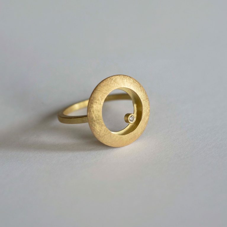 Anillo de oro con círculo abierto y diamante engastado en diseño contemporáneo