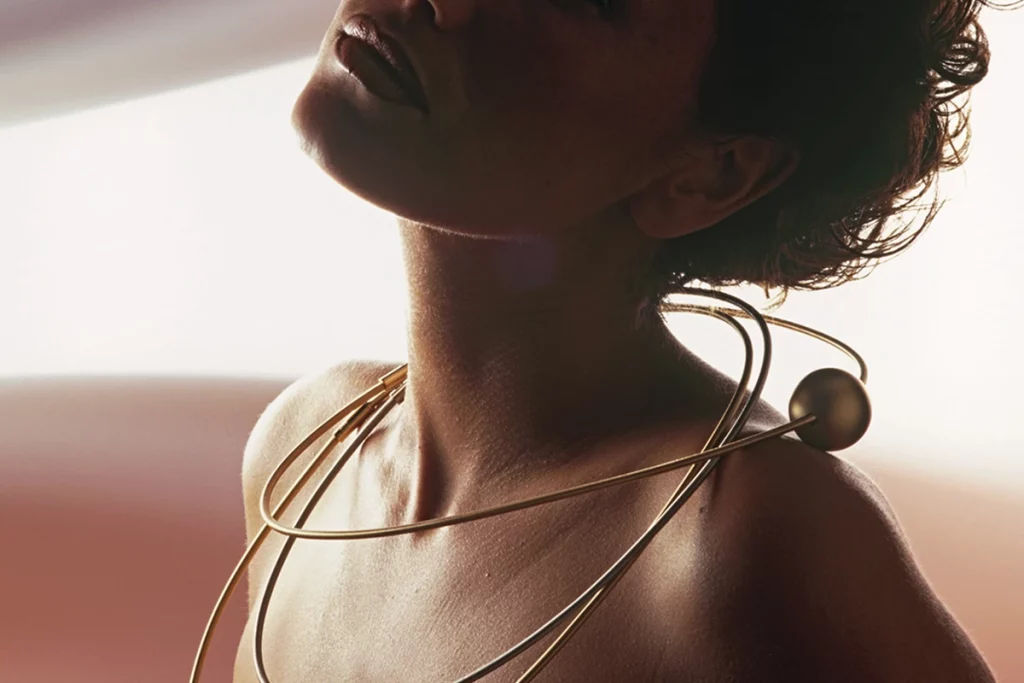 collar Niessing Coil en oro rodeando el cuello de una mujer con diseño contemporáneo sin cierre