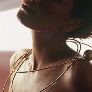 collar Niessing Coil en oro rodeando el cuello de una mujer con diseño contemporáneo sin cierre